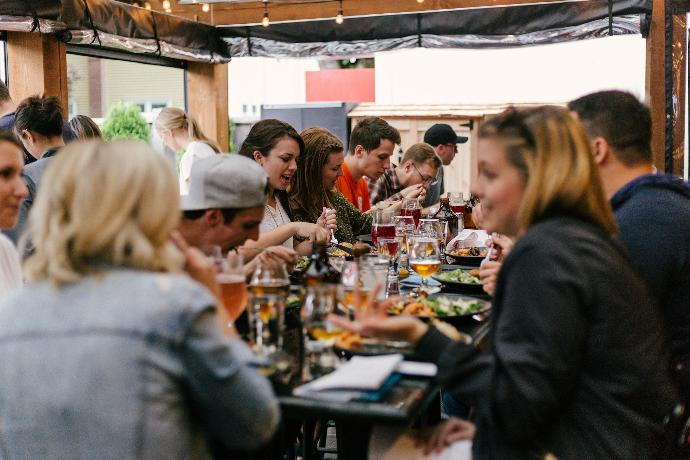 Menschen sitzen vor einem Tisch, unterhalten sich und essen Menschen sitzen vor einem Tisch, unterhalten sich und essen